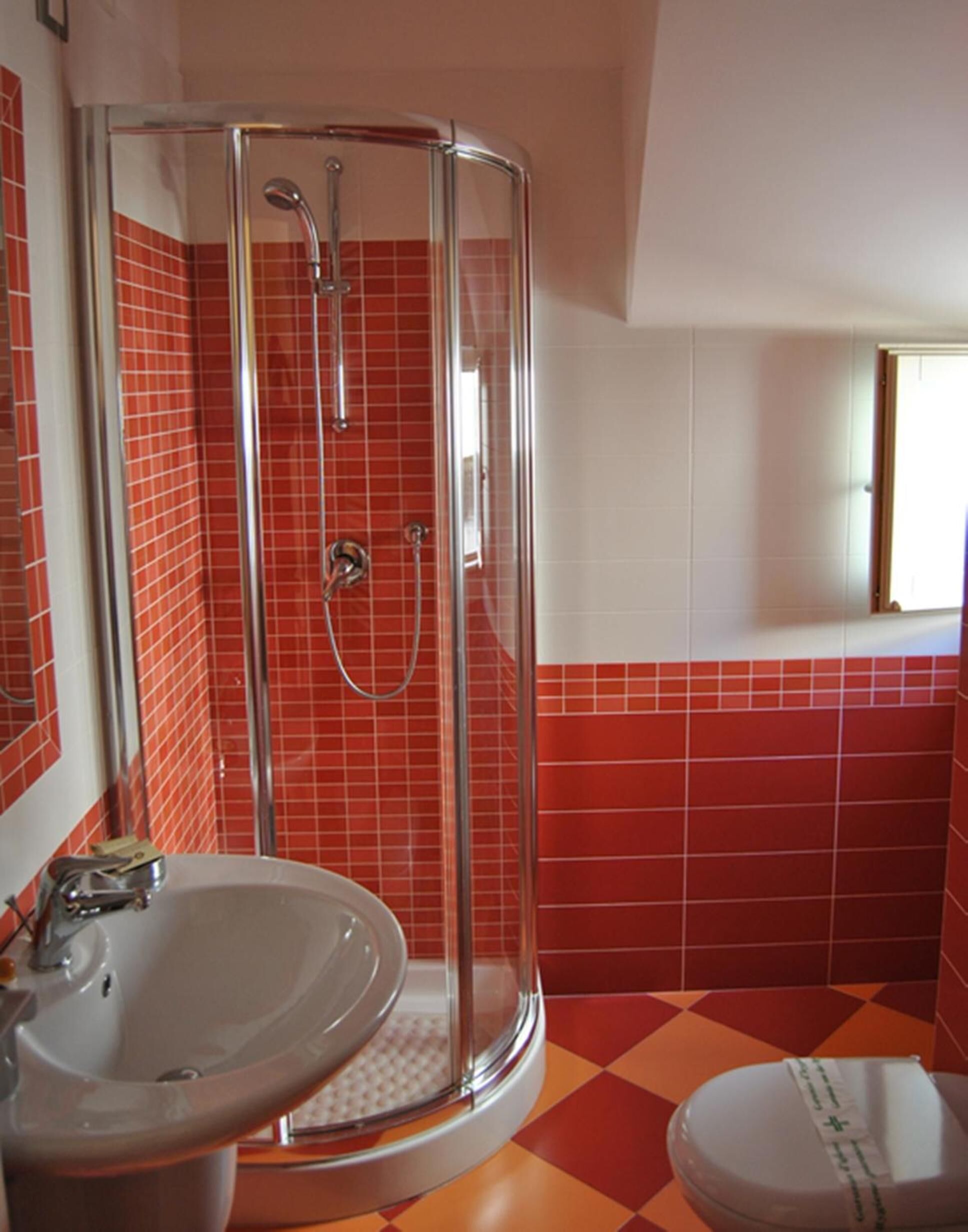 A bathroom with a glass-enclosed shower, a sink, and a toilet.