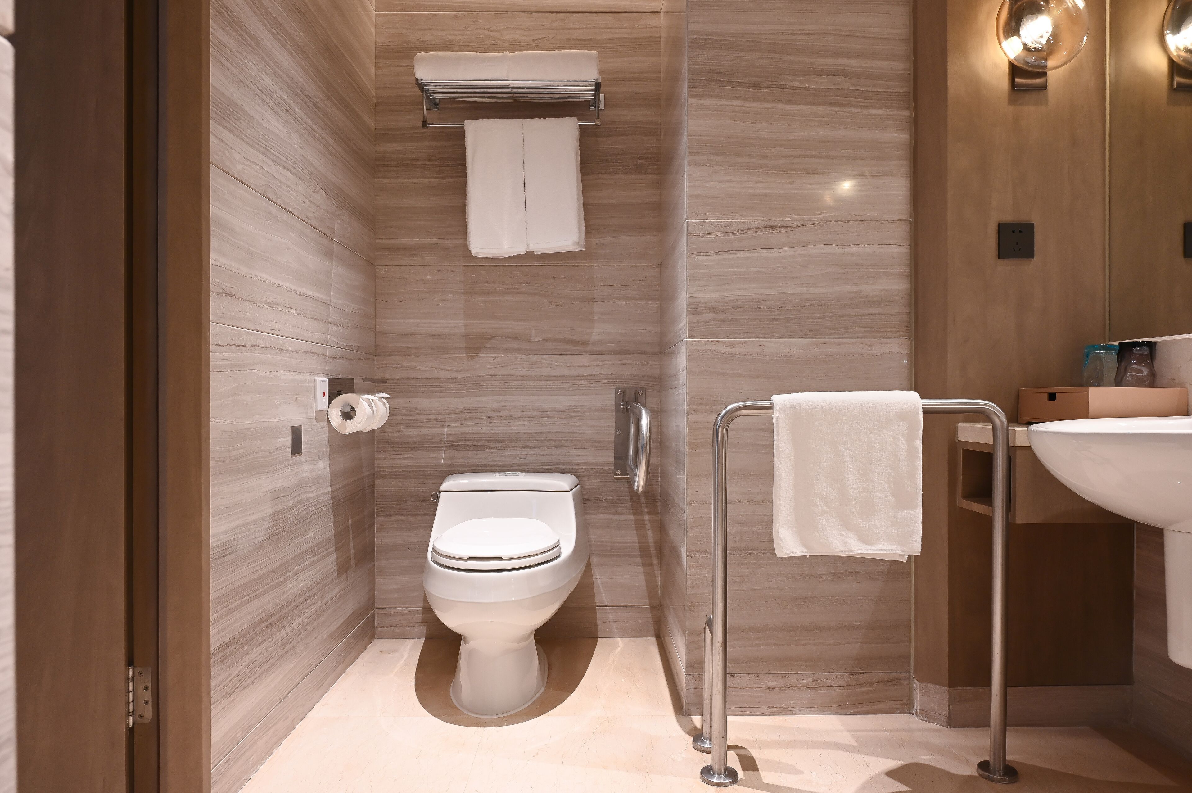 A modern bathroom with a toilet, towel rack, and sink.