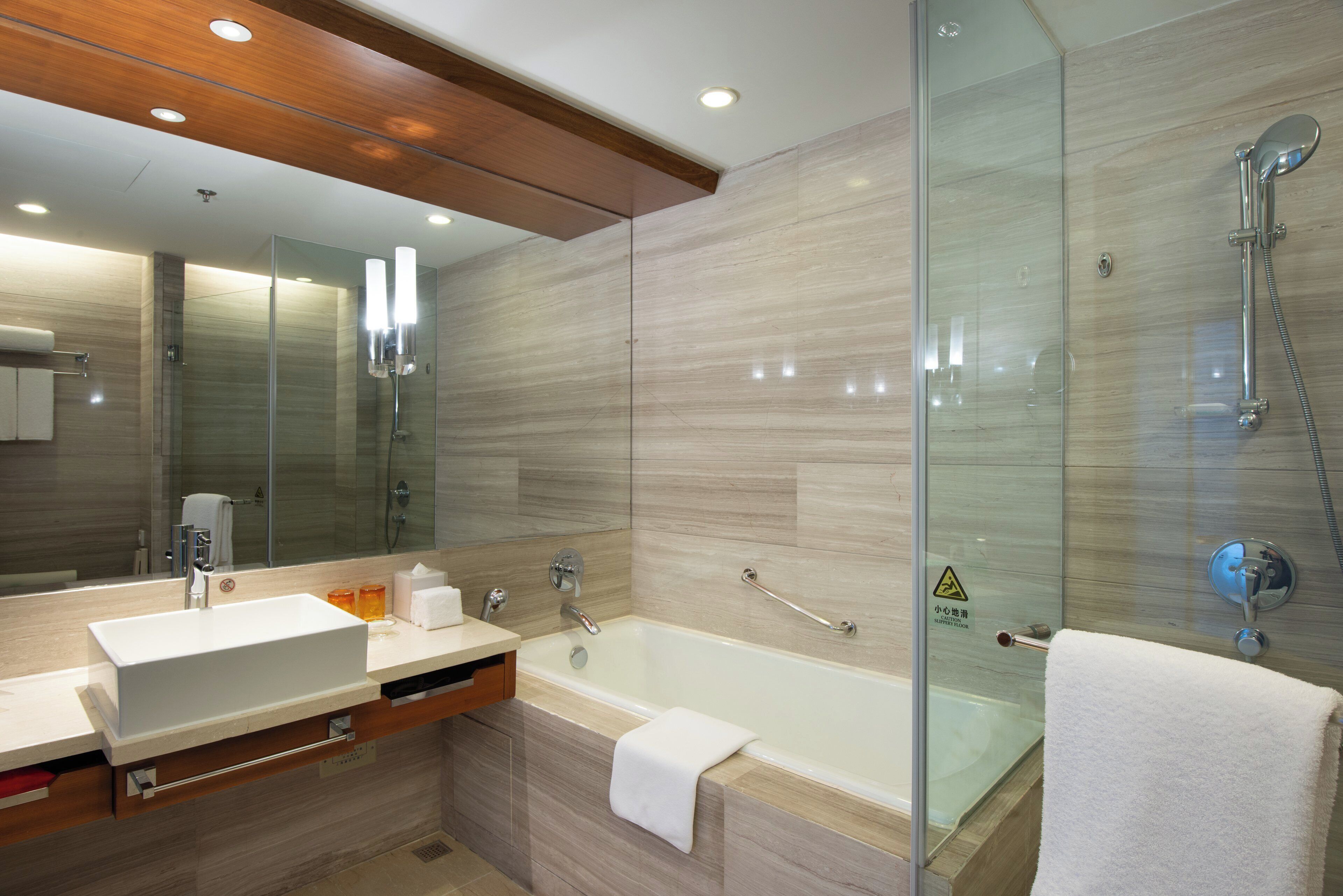 A modern bathroom with a glass-enclosed shower, a bathtub, and a vanity with a mirror.