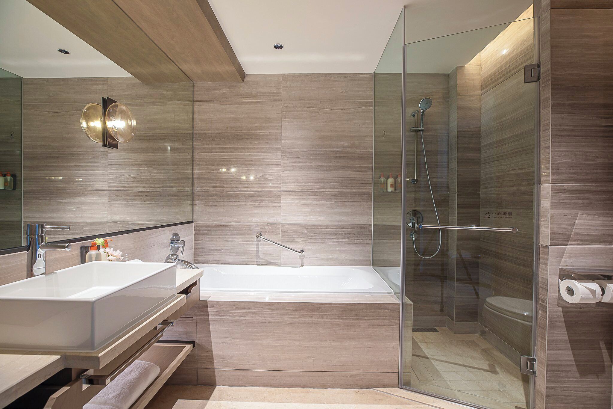 A modern bathroom with a large bathtub, a glass-enclosed shower, and a vanity with a sink and mirror.