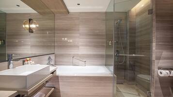 A modern bathroom with a large bathtub, a glass-enclosed shower, and a vanity with a sink and mirror.