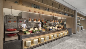 A modern buffet setup with a chef preparing food, a variety of dishes, and a well-lit, spacious layout. - Crowne Plaza Shanghai Jinxiu by IHG (Shanghai)
