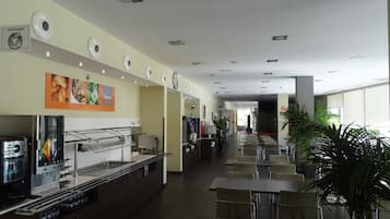 Una cafeteria àmplia amb diverses zones d'estar, una màquina de cafè i un mostrador de menjar.