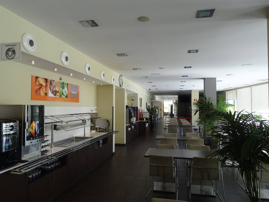Una cafeteria àmplia amb diverses zones d'estar, una màquina de cafè i un mostrador de menjar.