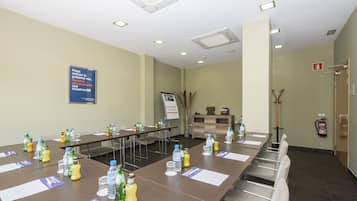 Un salón de conferencias con una mesa larga, botellas de agua y tarjetas de identificación.