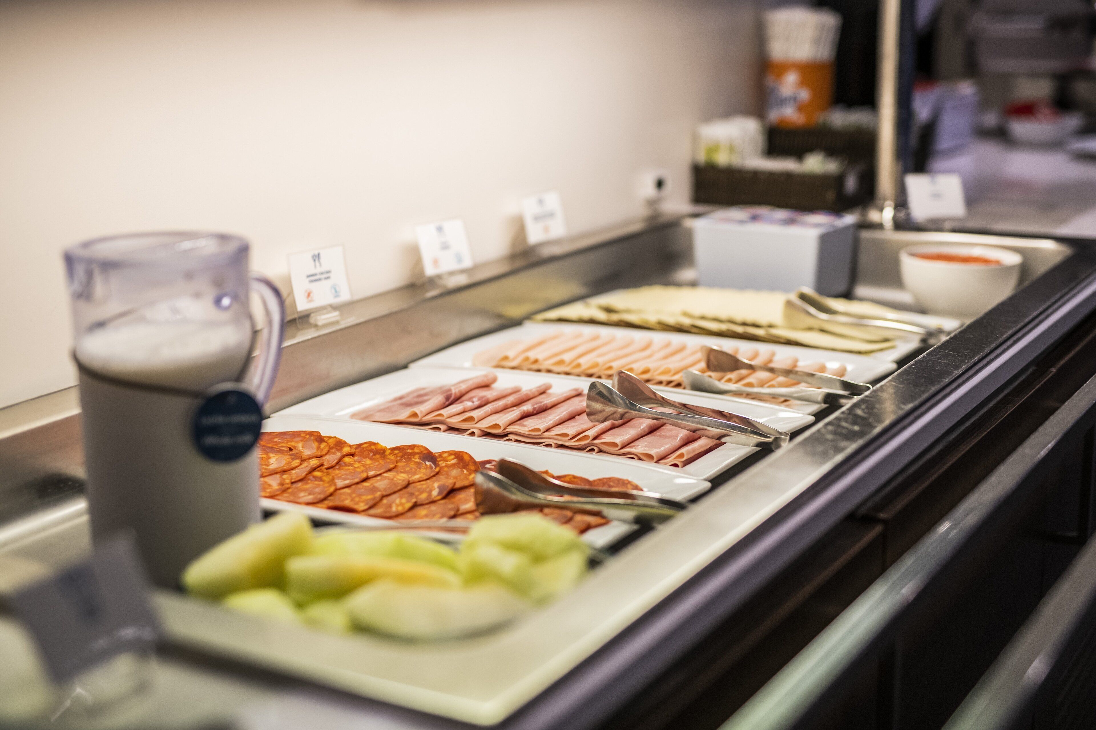 A buffet with various food items including meats, cheeses, and fruits.