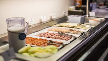 A buffet with various food items including meats, cheeses, and fruits.