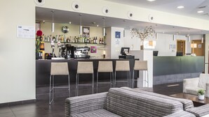 Un moderno vestíbulo de hotel con zona de bar, asientos y mostrador de recepción.
