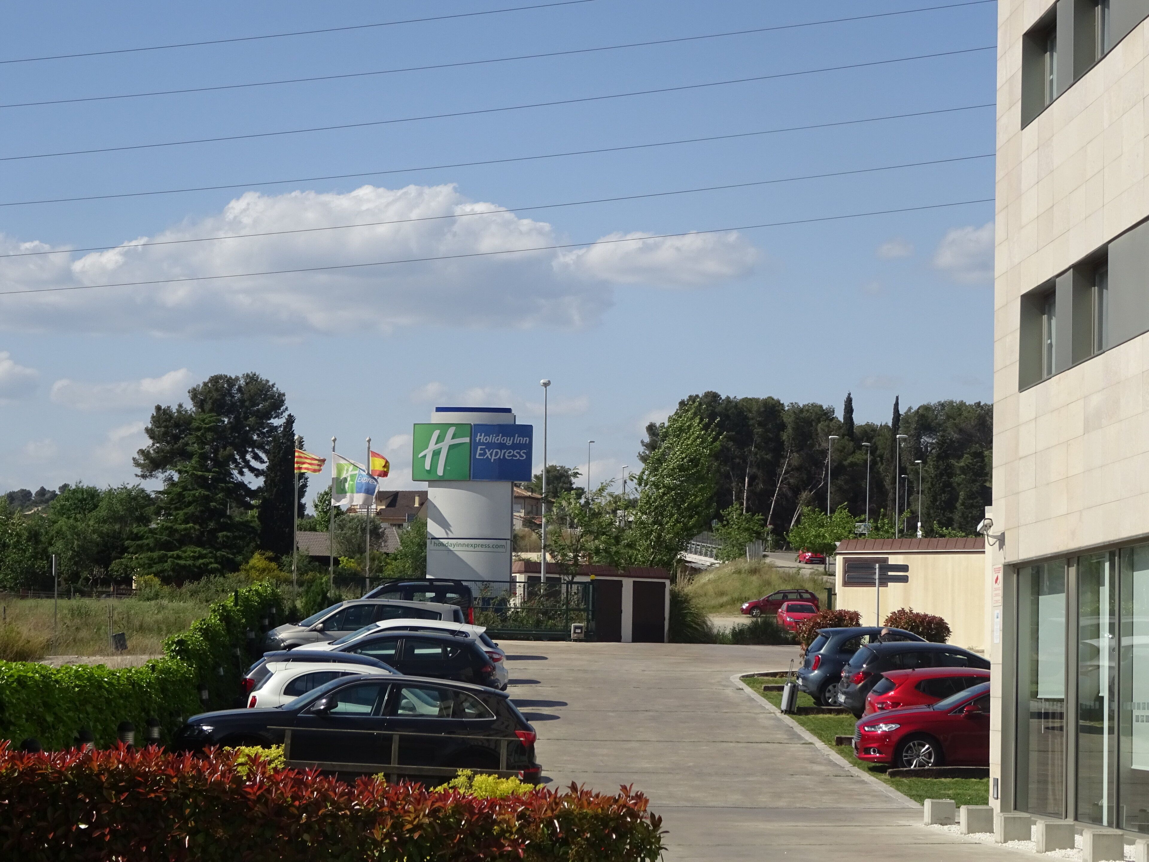 Un parking rempli de voitures, une enseigne « Holiday Inn Express » et un bâtiment à l’architecture moderne.