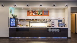 Una mesa de buffet con diversos alimentos, un dispensador de bebidas y una máquina de café.