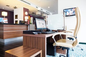 A hotel reception desk with a computer, a telephone, and a chair. - Holiday Inn Express Guetersloh by IHG (Guetersloh)