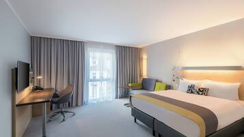 Een hotelkamer met een bed, een bureau, een stoel, een televisie en een raam met gordijnen.