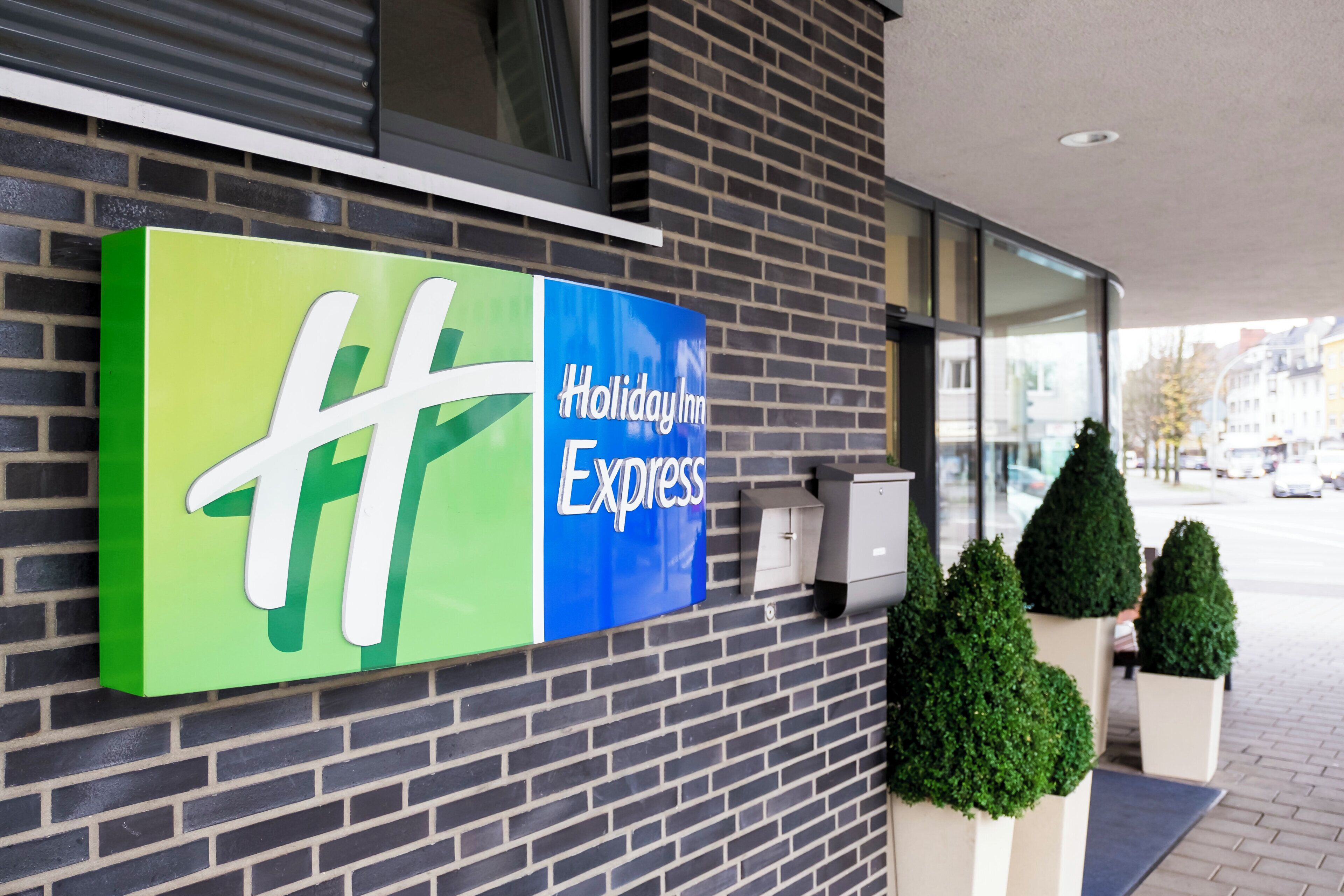 Een hotelingang met een groen en blauw bord waarop 'Holiday Inn Express' staat.