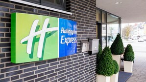 A hotel entrance with a green and blue sign indicating the name 'Holiday Inn Express'. - Holiday Inn Express Guetersloh by IHG (Guetersloh)
