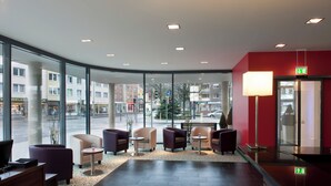 A lobby with seating, a reception desk, and large windows offering a view of the street. - Holiday Inn Express Guetersloh by IHG (Guetersloh)