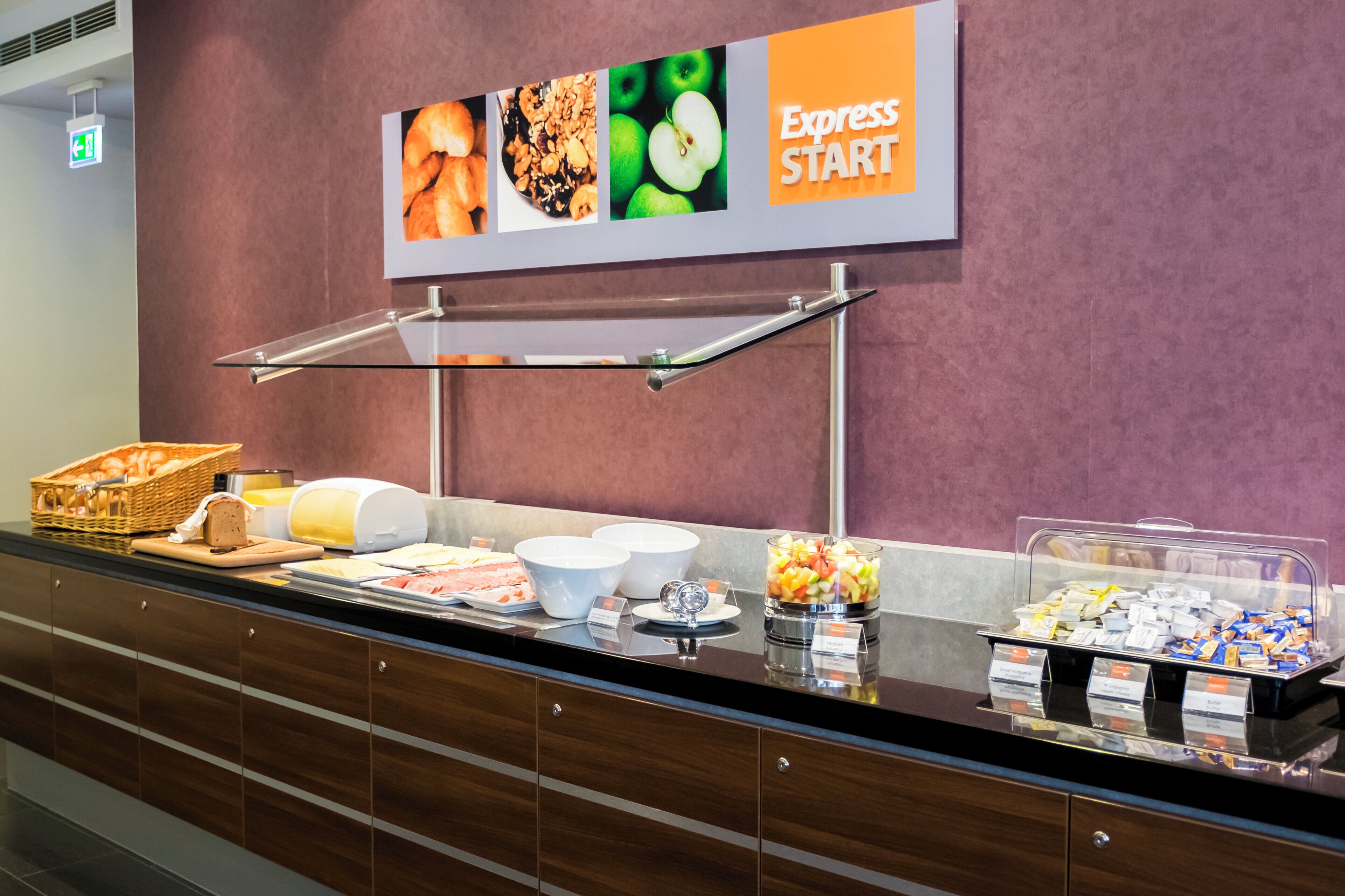Ein Buffet mit verschiedenen Speisen, ein Schild mit der Aufschrift 'Express Start' und ein an der Wand befestigtes Notausgangsschild.