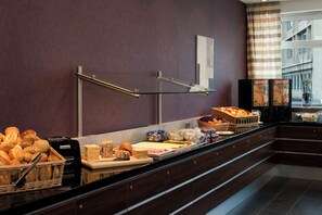 A buffet counter with various food items, a glass display case, and a coffee machine. - Holiday Inn Express Guetersloh by IHG (Guetersloh)