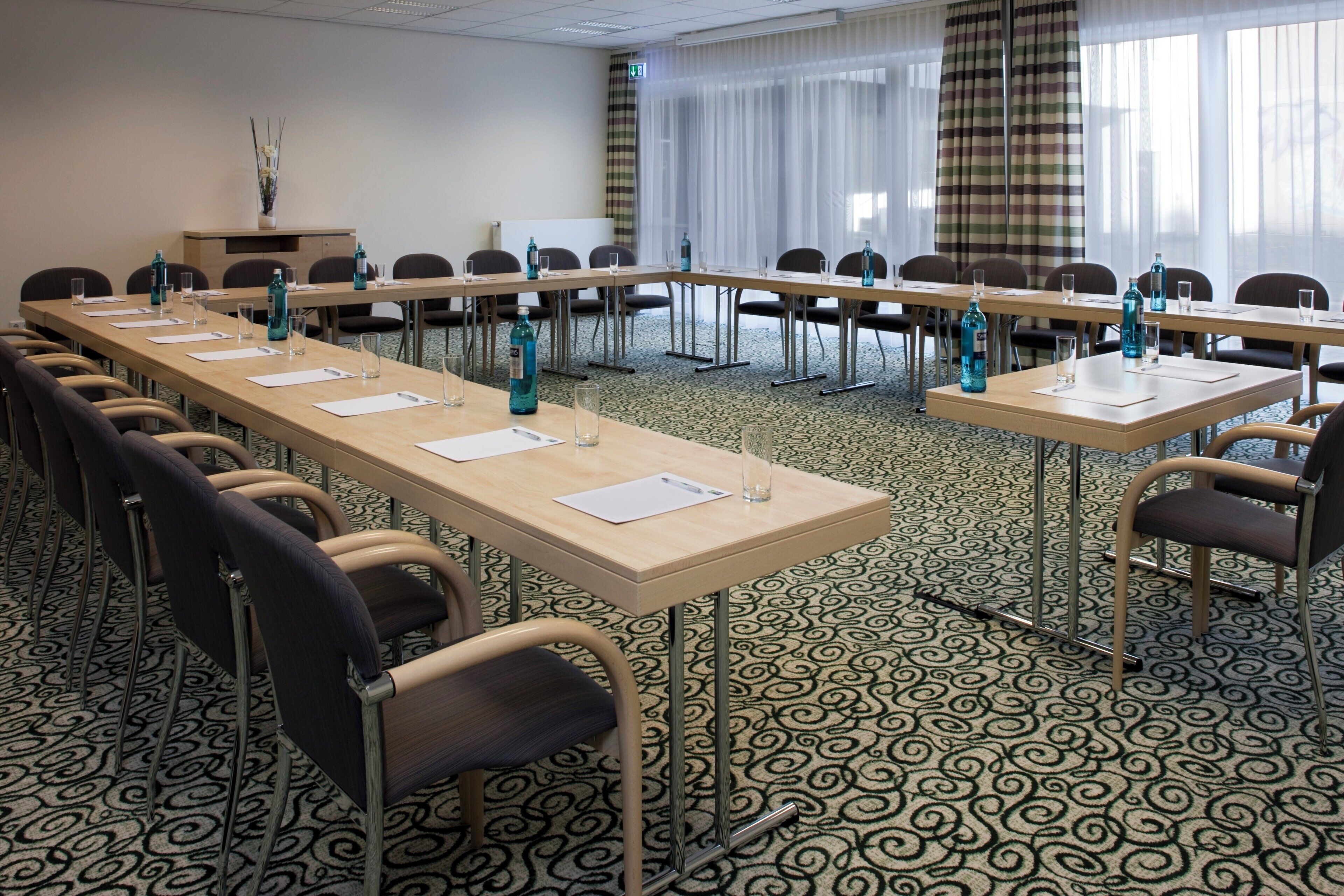 Ein Konferenzraum mit langen Tischen, Stühlen und Wasserflaschen.