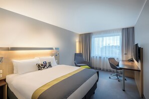 A hotel room with a large bed, a desk with a chair, a TV, and a window with curtains. - Holiday Inn Express Guetersloh by IHG (Guetersloh)