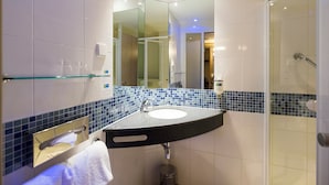 A modern bathroom with a glass shower enclosure, a curved sink with a black countertop, and a mirror above the sink.