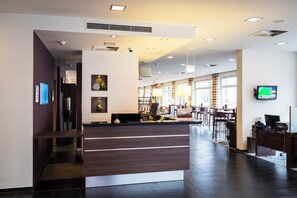 Ein Hotel-Rezeptionsbereich mit modernem Design, inklusive einer Rezeption, einer Sitzgelegenheit und einem großen Fenster, das für natürliches Licht sorgt.