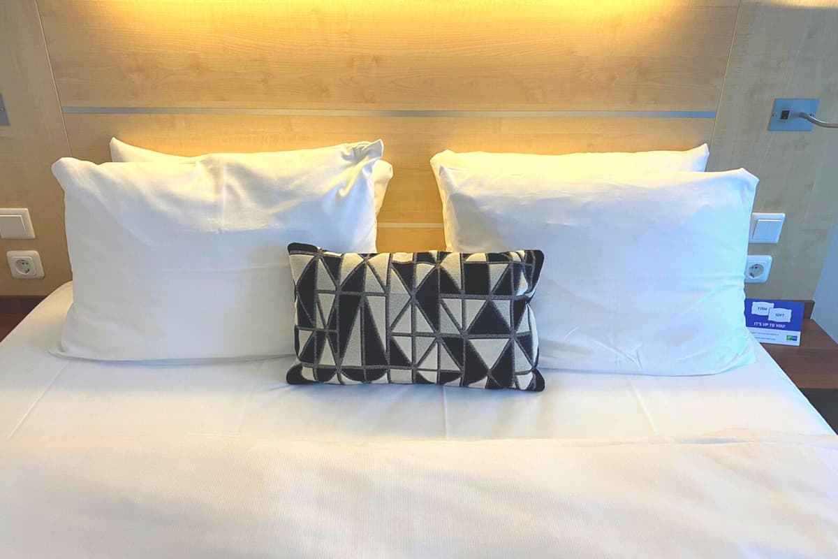 A bed with white pillows and a black and white patterned pillow.