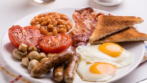 A plate of breakfast food including eggs, sausages, tomatoes, beans, toast, and bacon. - Avani Deira Dubai Hotel (Dubai)