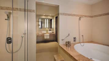 Een moderne badkamer met een douchecabine van glas, een vrijstaand bad en een wastafel met twee wasbakken.
