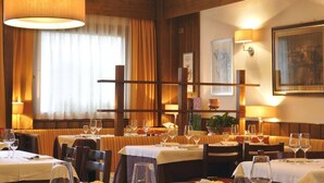 A restaurant with wooden paneling, white tablecloths, and candlelit ambiance. - Hotel Sassella (Grosio)