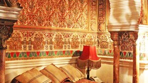 Una habitación con una cama, una lámpara roja y un muro decorativo con diseños elaborados.