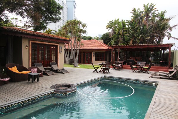 Relax by the serene pool surrounded by lush tropical vegetation and a comfortable wooden deck.