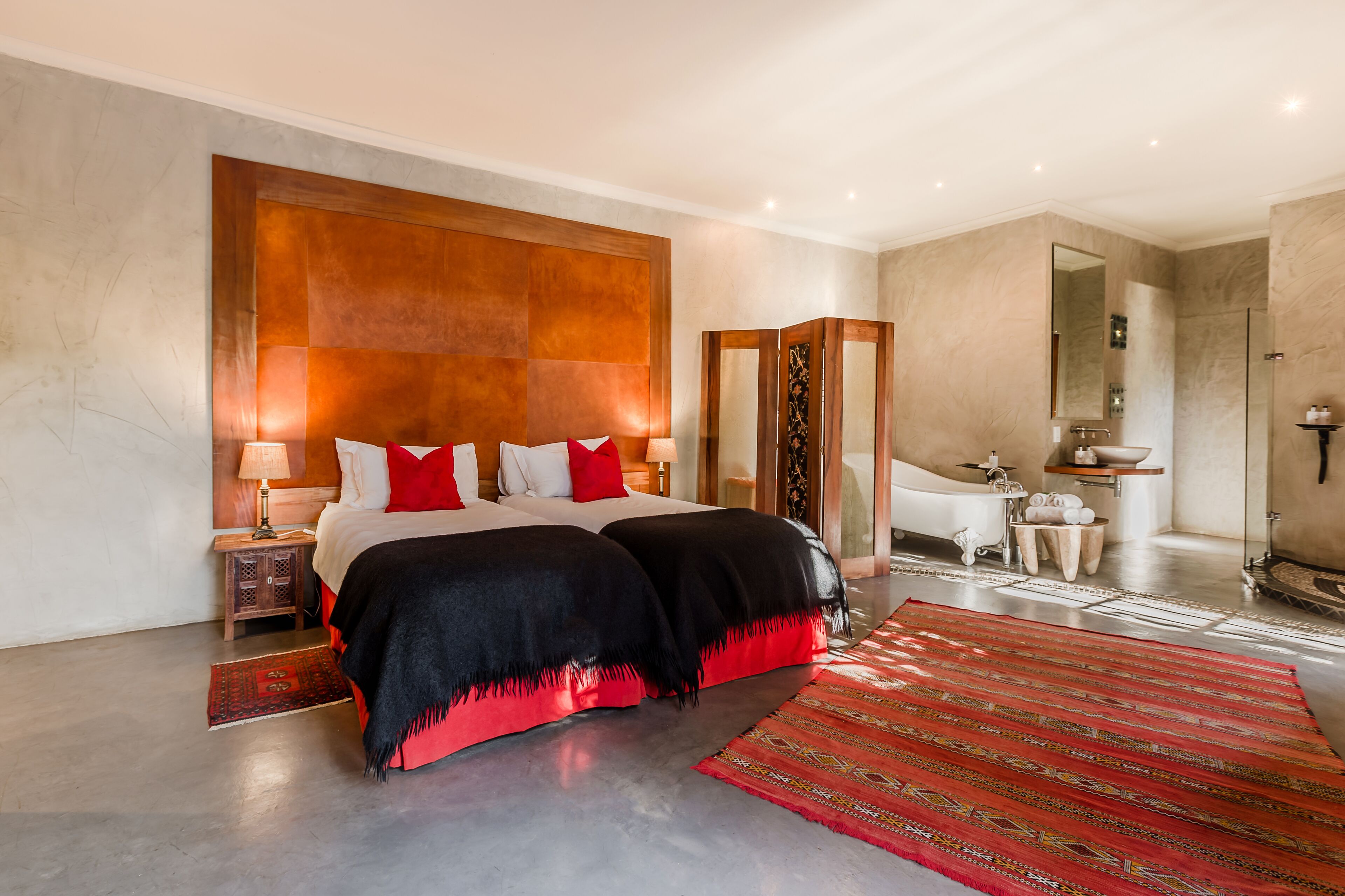 Quarto de hotel moderno com uma cama grande, um banheiro com banheira e um espelho amplo.