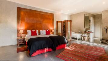 Quarto de hotel moderno com uma cama grande, um banheiro com banheira e um espelho amplo.
