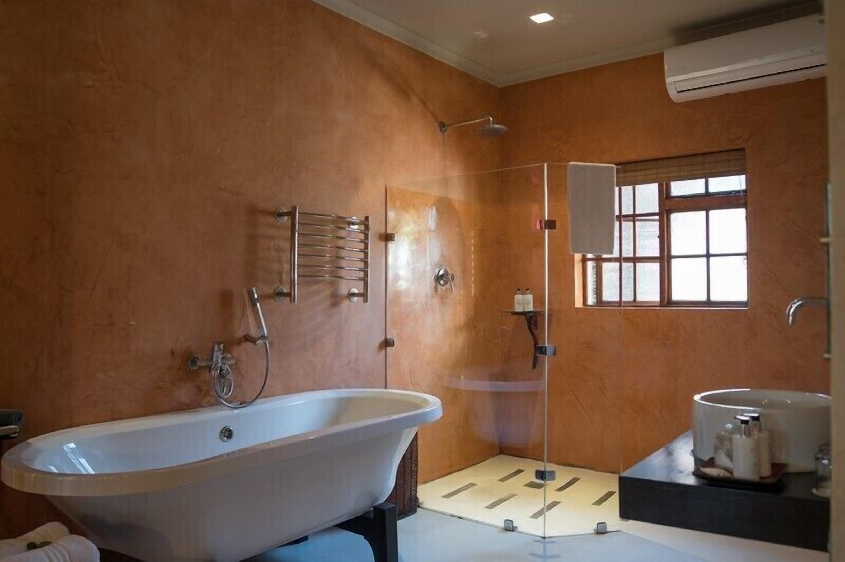 A bathroom with a freestanding bathtub, a glass-enclosed shower, and a window providing natural light.