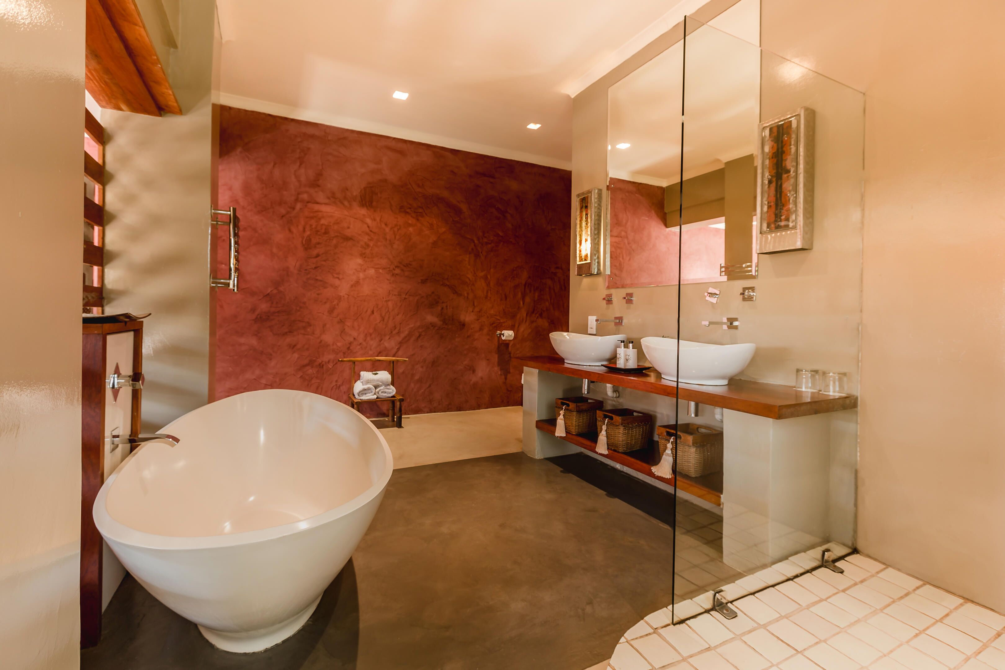 A modern bathroom with a freestanding bathtub, a glass-enclosed shower, and a vanity with a large sink and shelves.