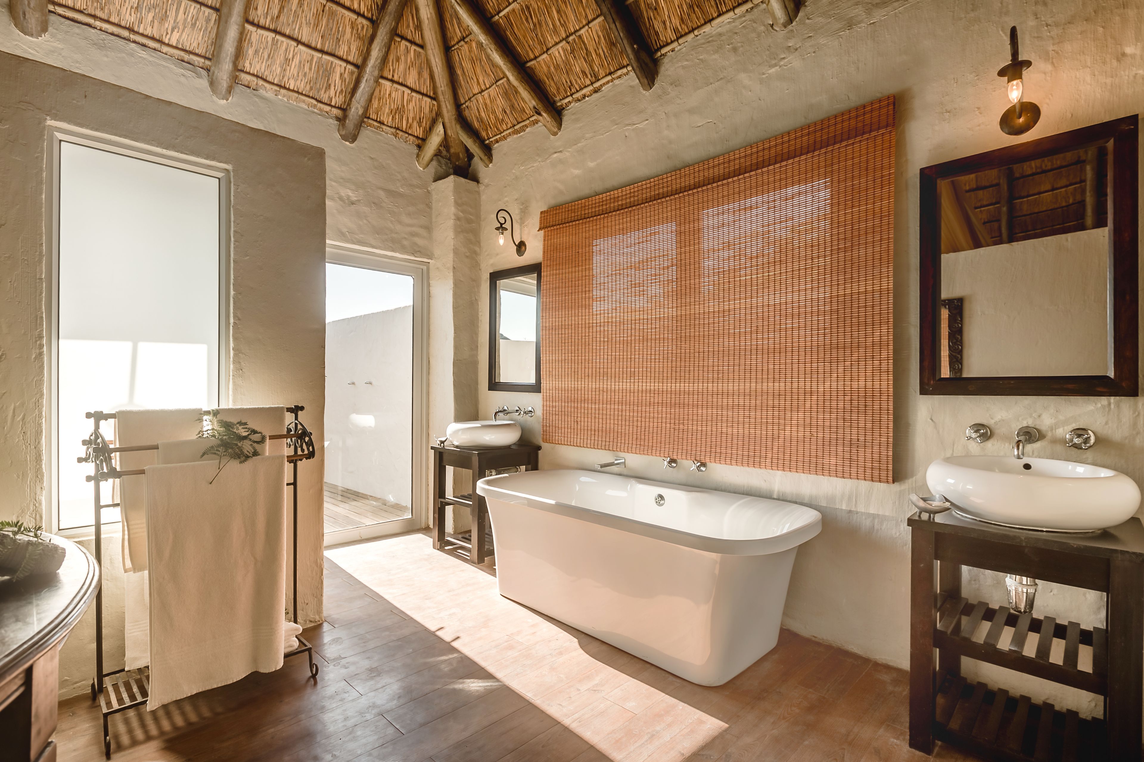 A bathroom with a bathtub, two sinks, a mirror, and a towel rack.