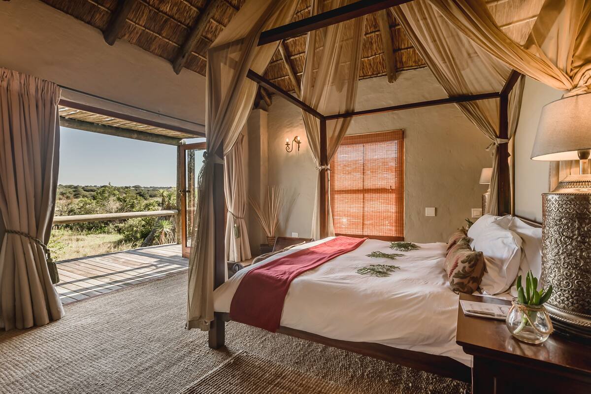 Un dormitorio espacioso con una cama grande, dosel y vistas al exterior.