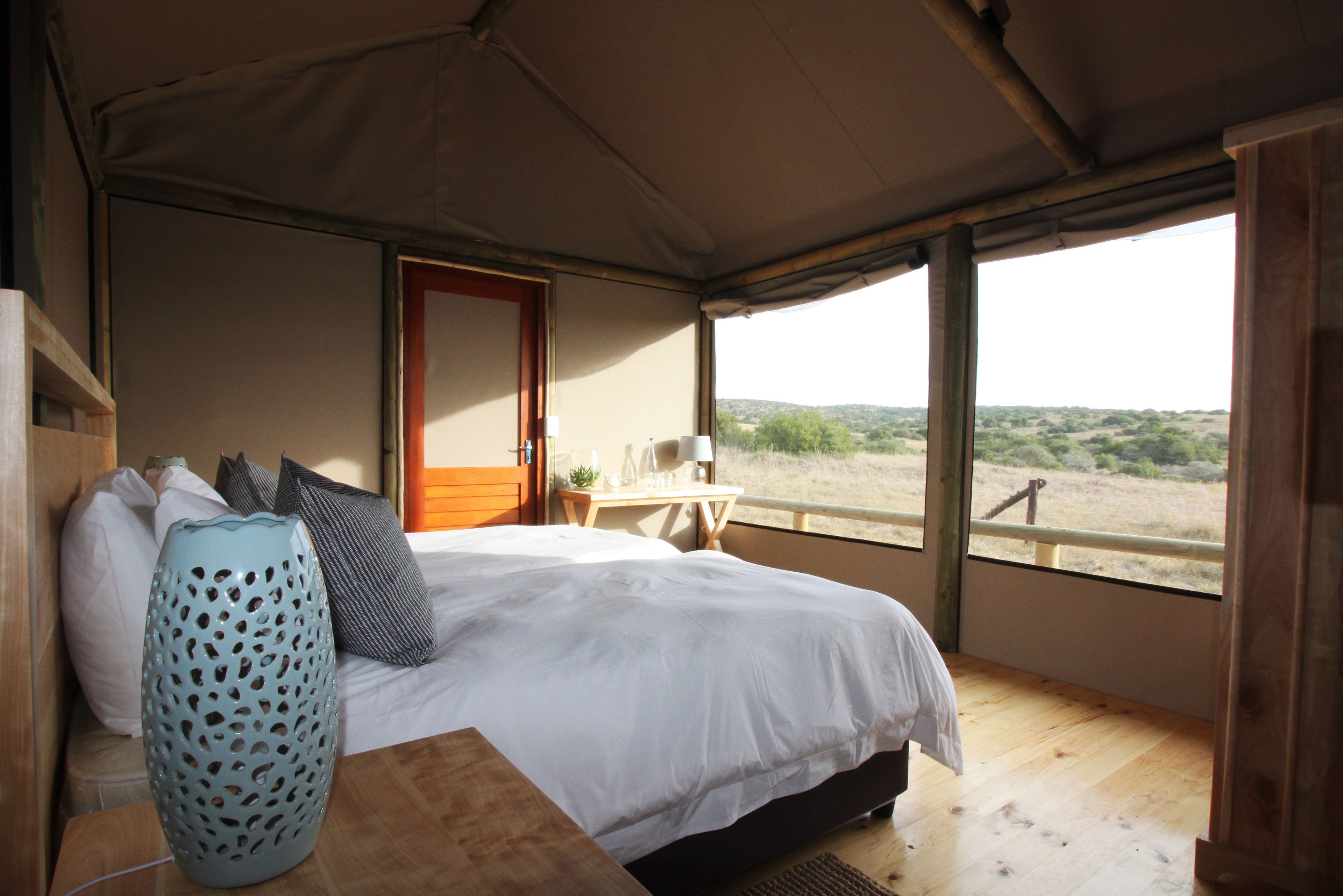 Ein Schlafzimmer mit Bett, Tisch und Fenster mit Blick ins Freie.