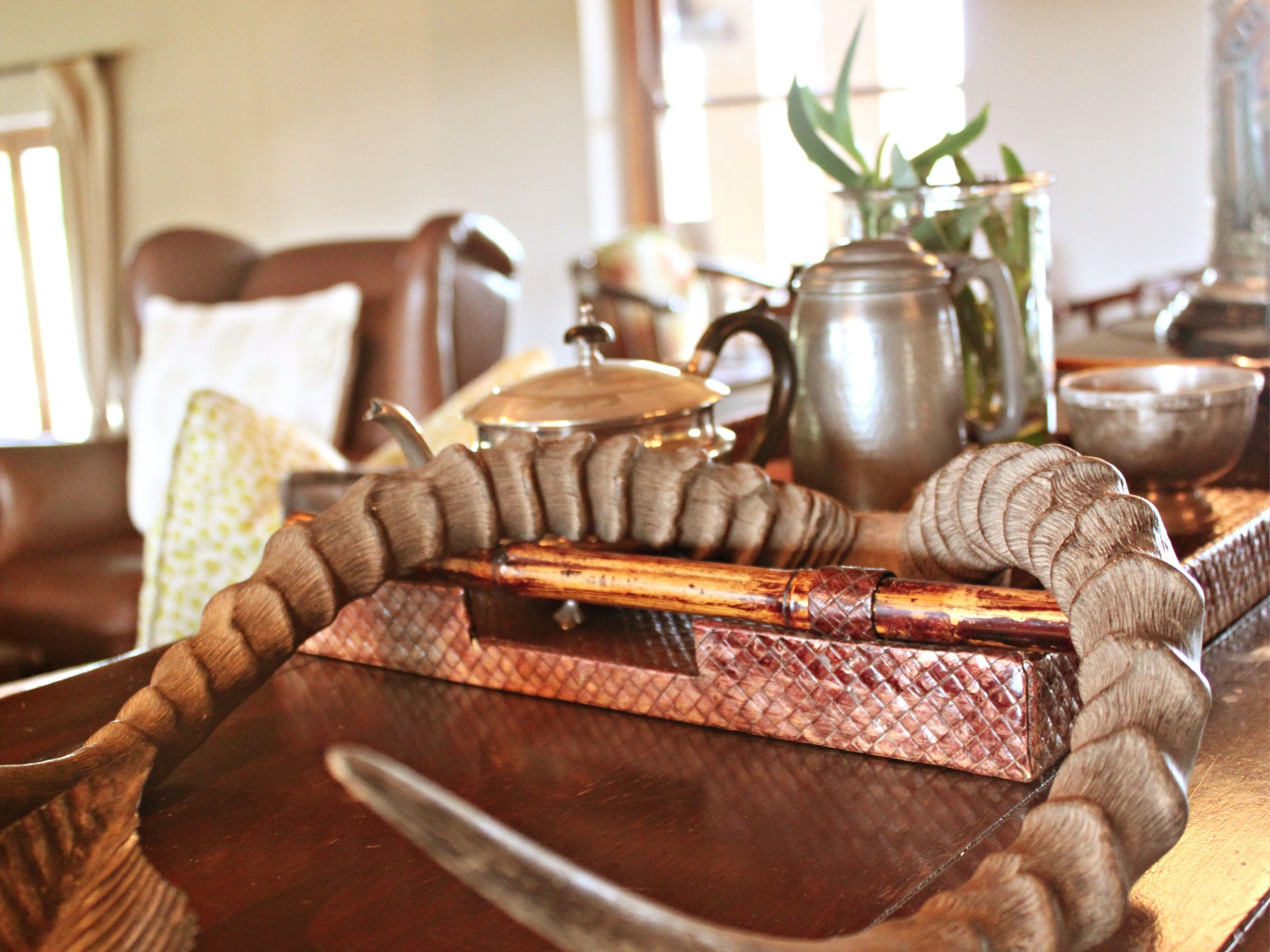 A wooden tray with a woven edge, a metal pot, and a wooden spoon.