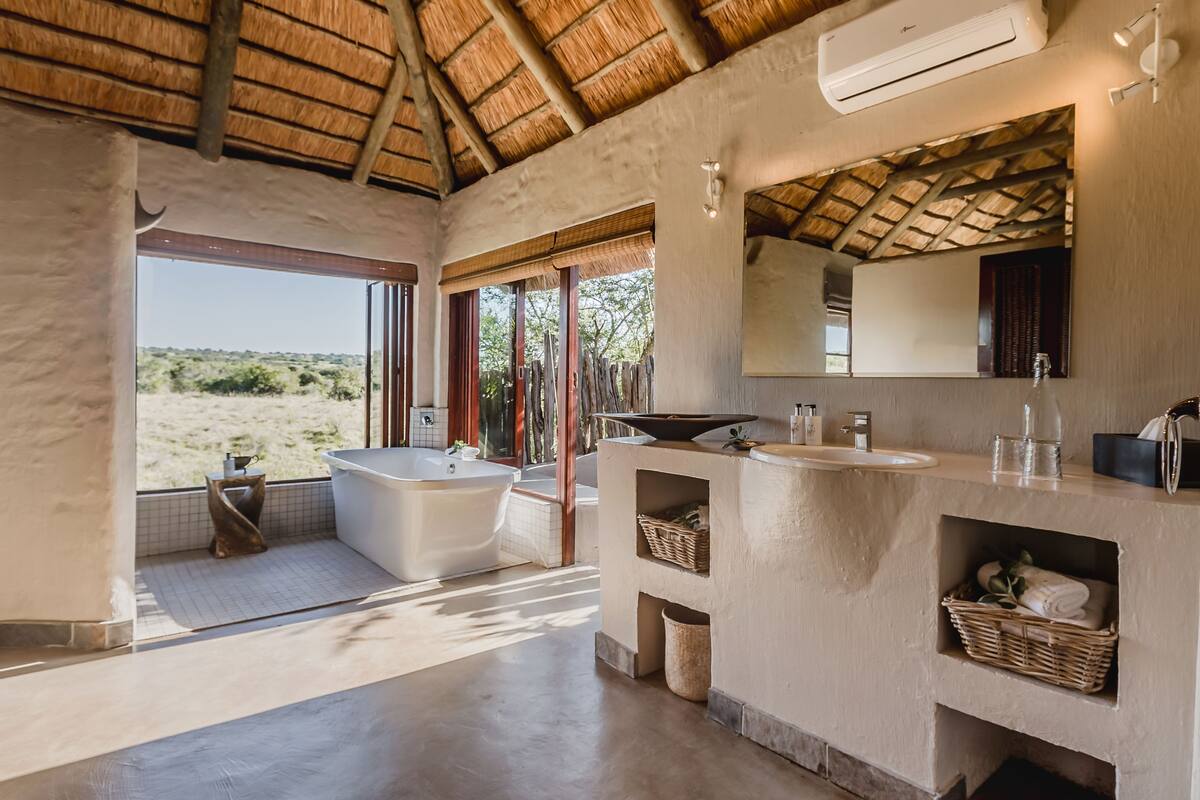Un baño moderno con una bañera grande, un lavabo y un espejo. Tiene vistas al exterior.