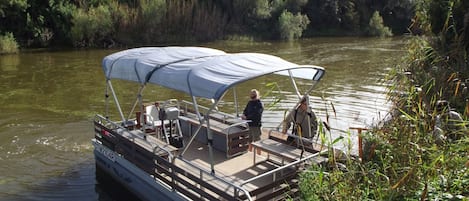 Un bote con una zona de estar cubierta y una persona de pie en la proa.