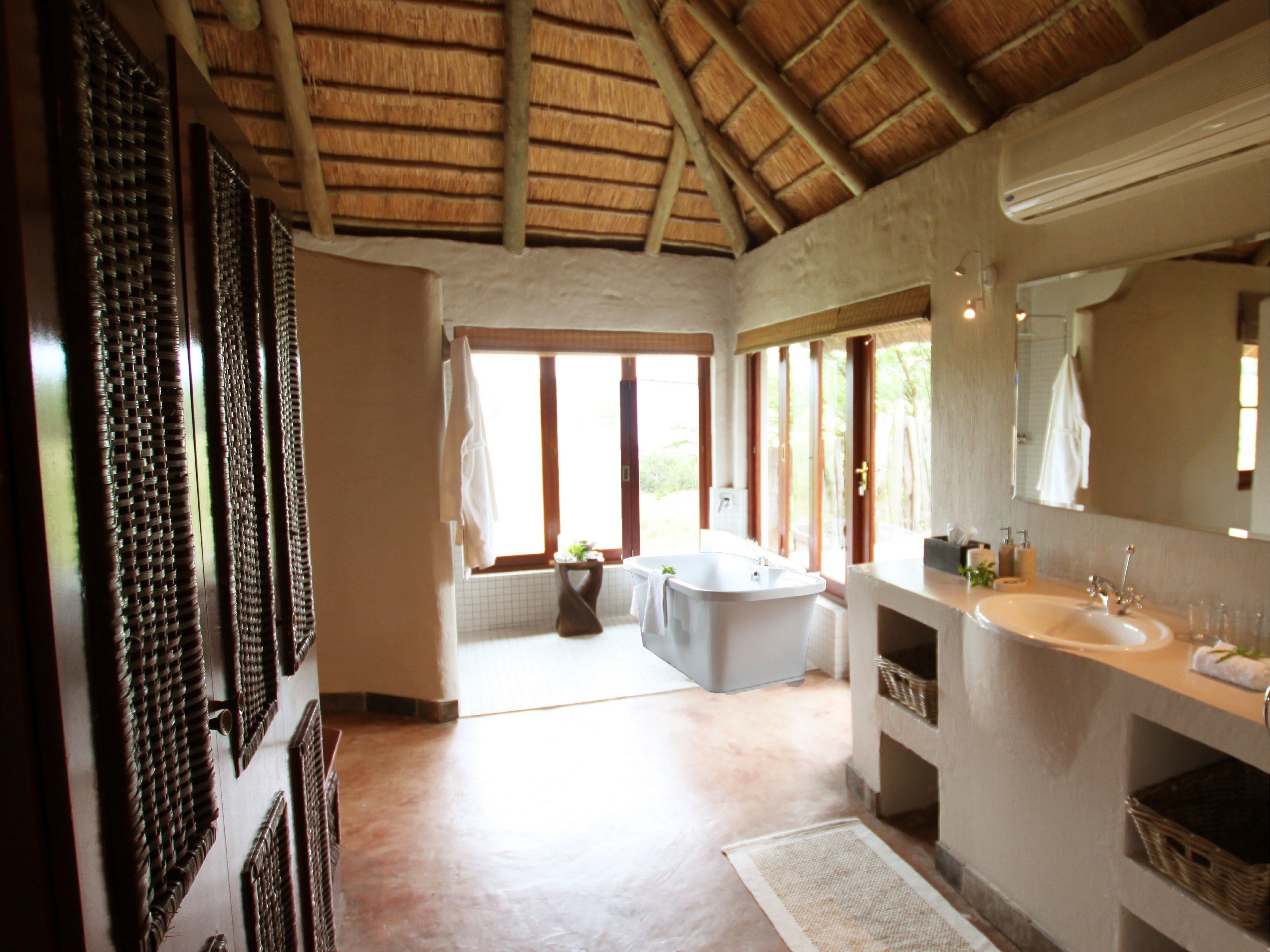 A bathroom with a large bathtub, a double sink, and a large mirror.