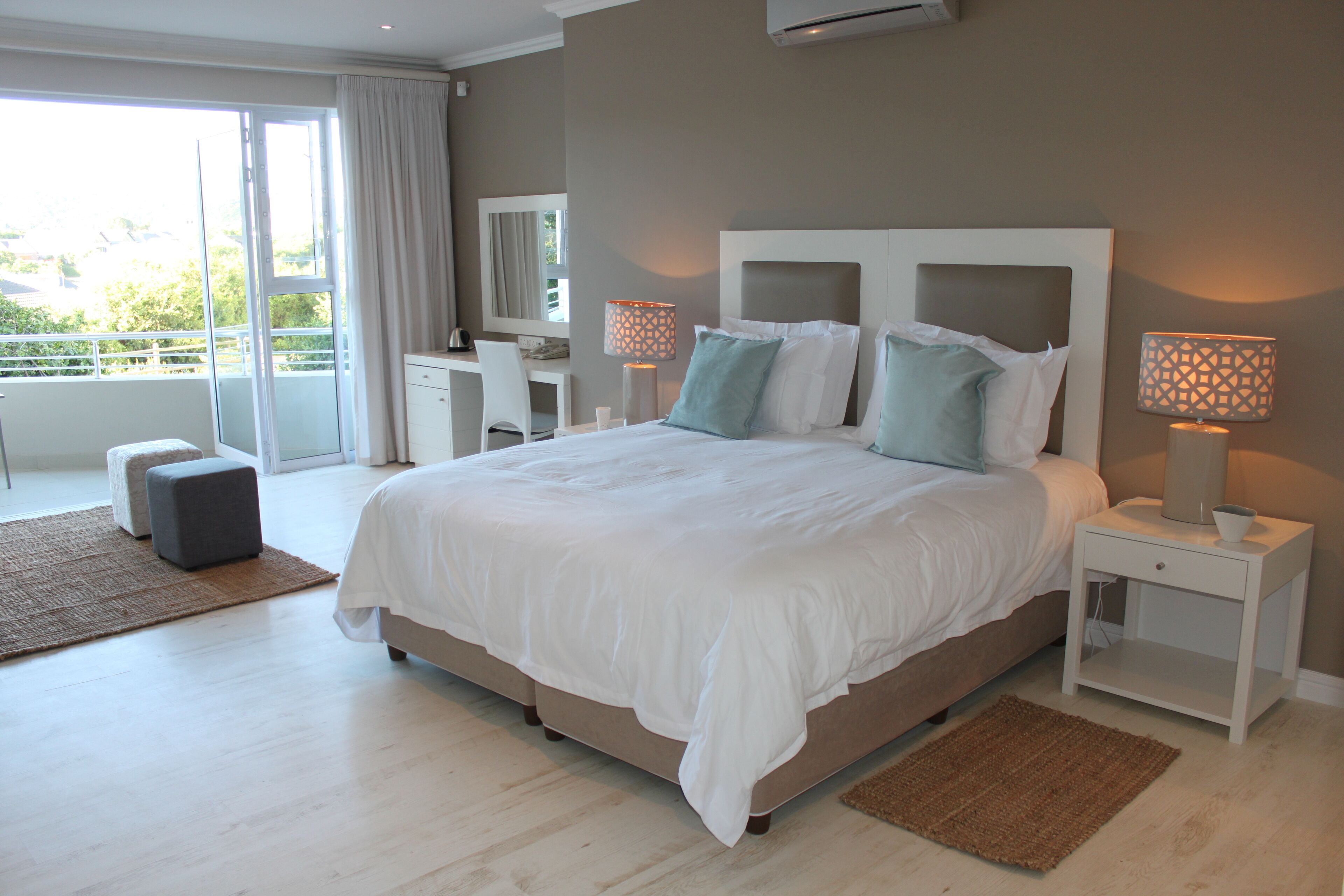 A modern bedroom with a large bed, two bedside tables with lamps, a desk, and a chair.