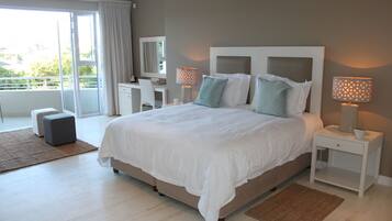 A modern bedroom with a large bed, two bedside tables with lamps, a desk, and a chair.