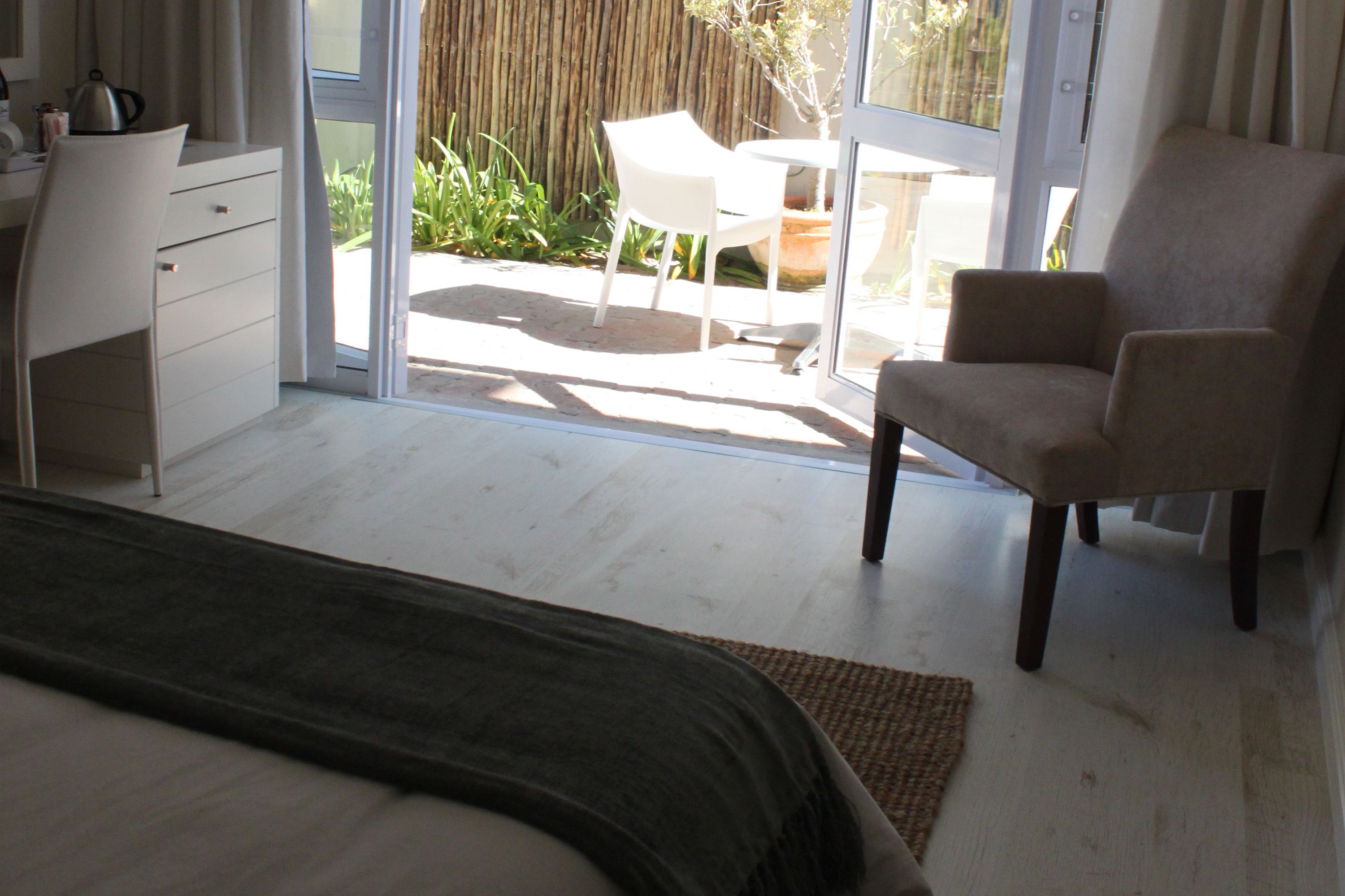 Un dormitorio con cama, escritorio, silla y vista al patio exterior.