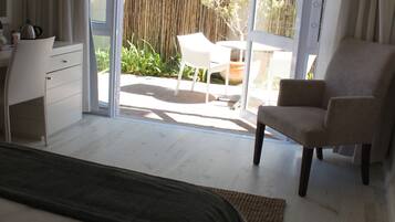 Un dormitorio con cama, escritorio, silla y vista al patio exterior.