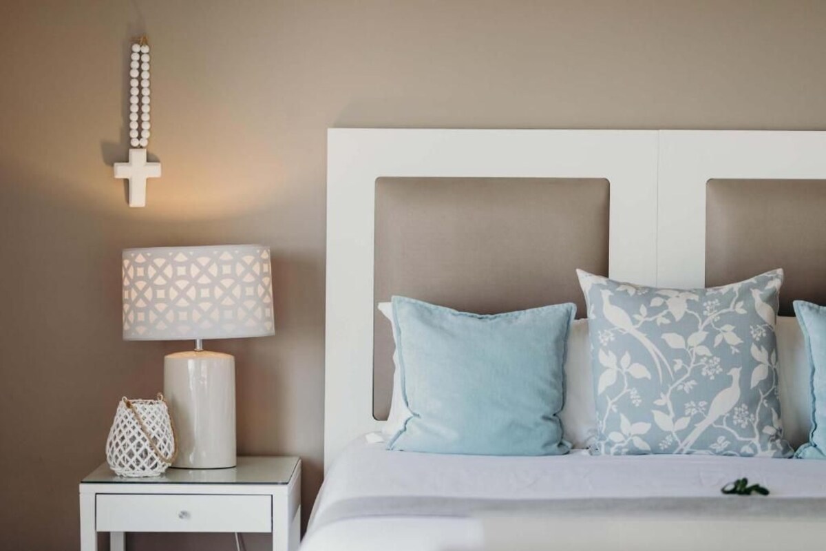 Une chambre à coucher avec un lit, une table de chevet, une lampe et un crucifix fixé au mur.