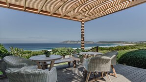 Une terrasse extérieure aménagée avec des meubles en osier et offrant une vue sur l’océan.
