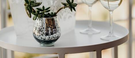 Una mesa con una botella de champán, dos copas y un jarrón decorativo con plantas.