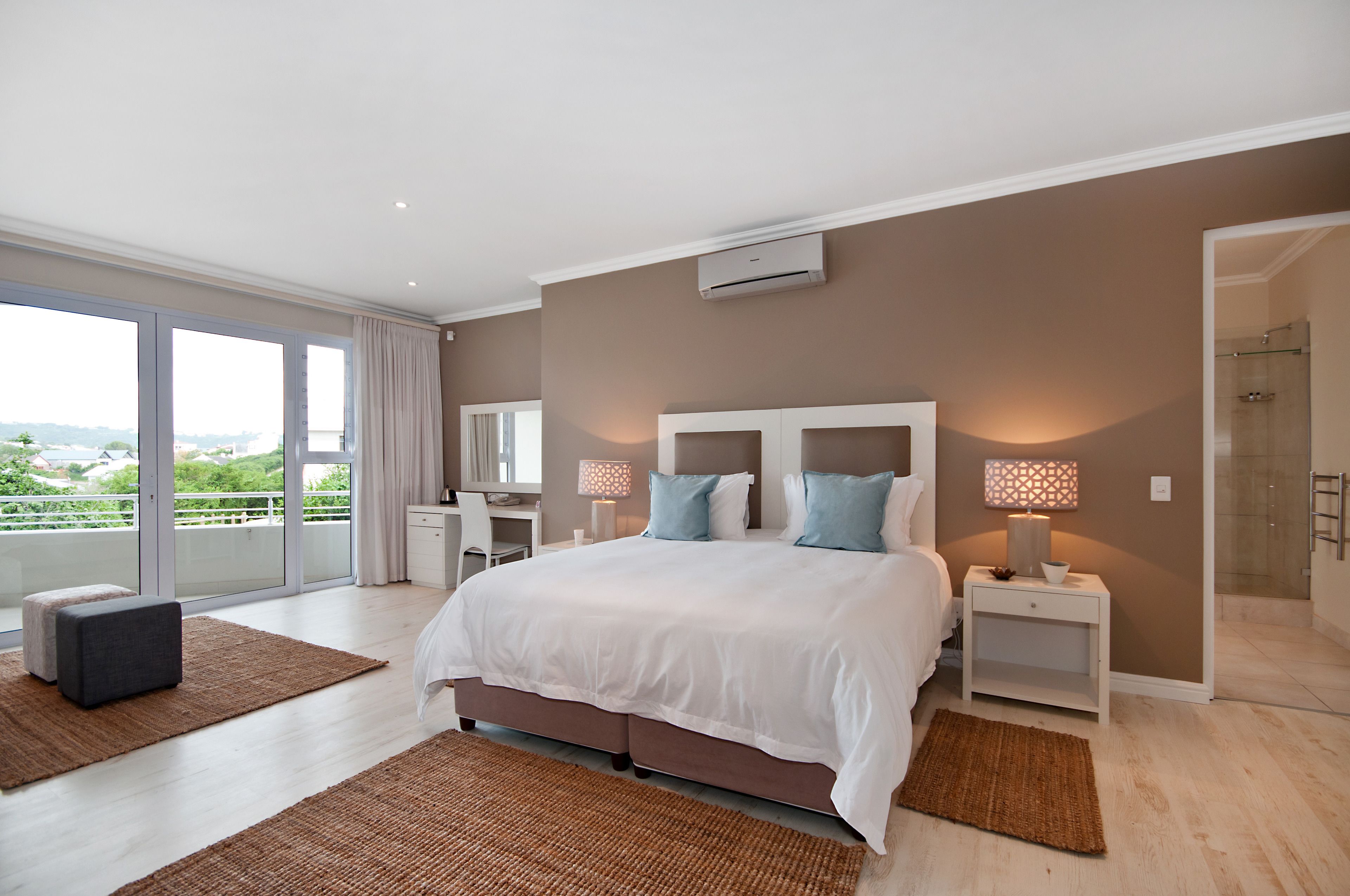 A modern bedroom with a large bed, a desk, and a walk-in closet.